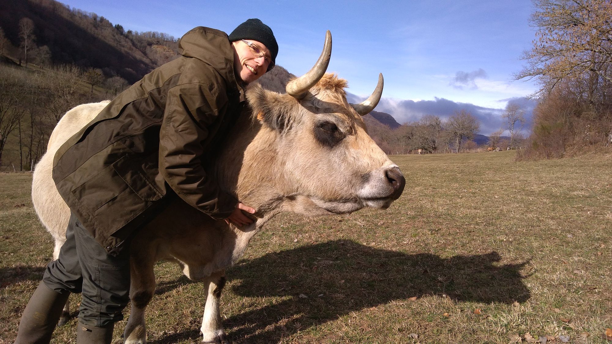 Bastien, éleveur et créateur de BAO, dans un pâturage du Cantal avec l'une de ses vaches